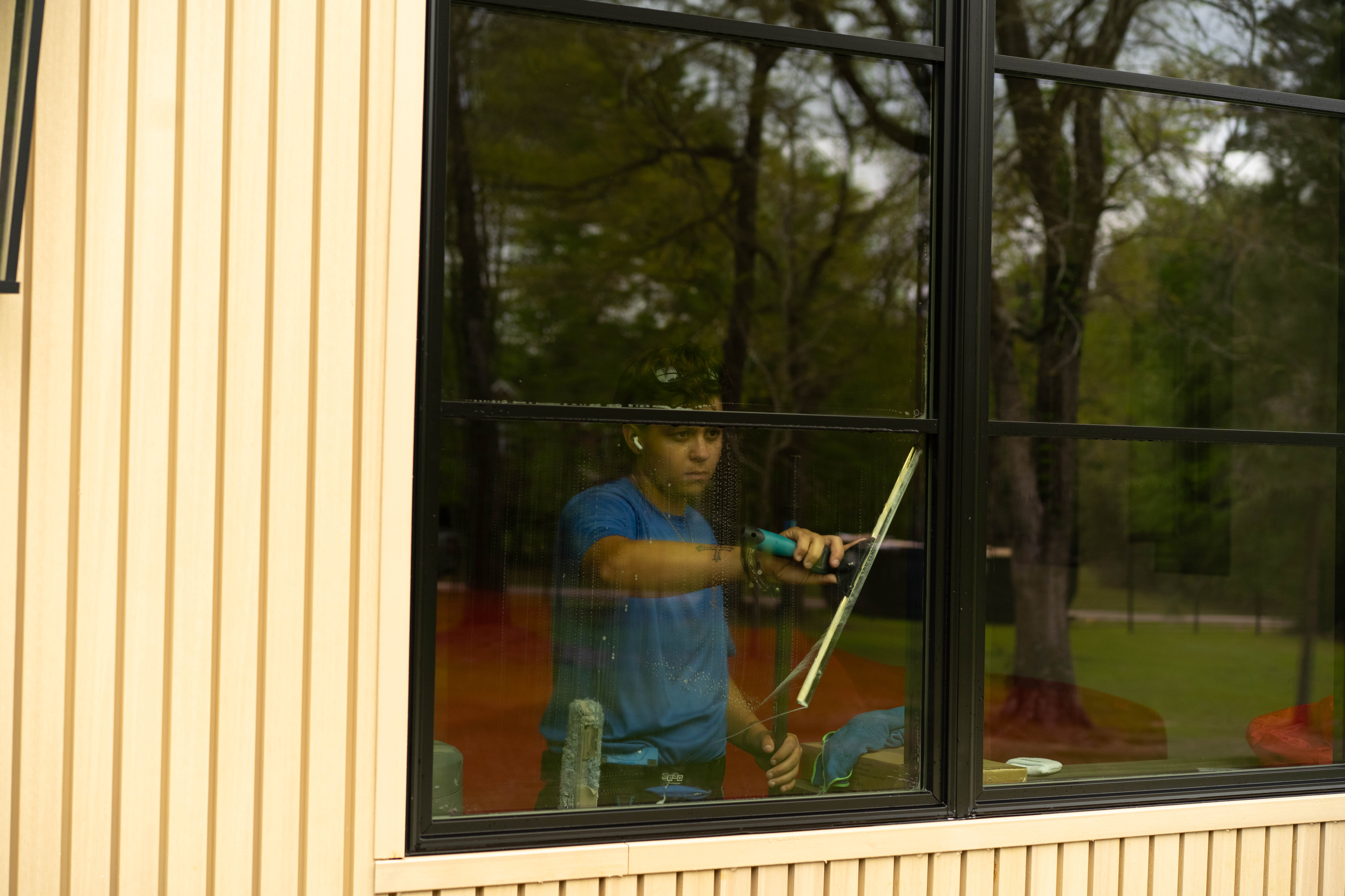 Window Warriors technician cleaning interior glass with a squeegee