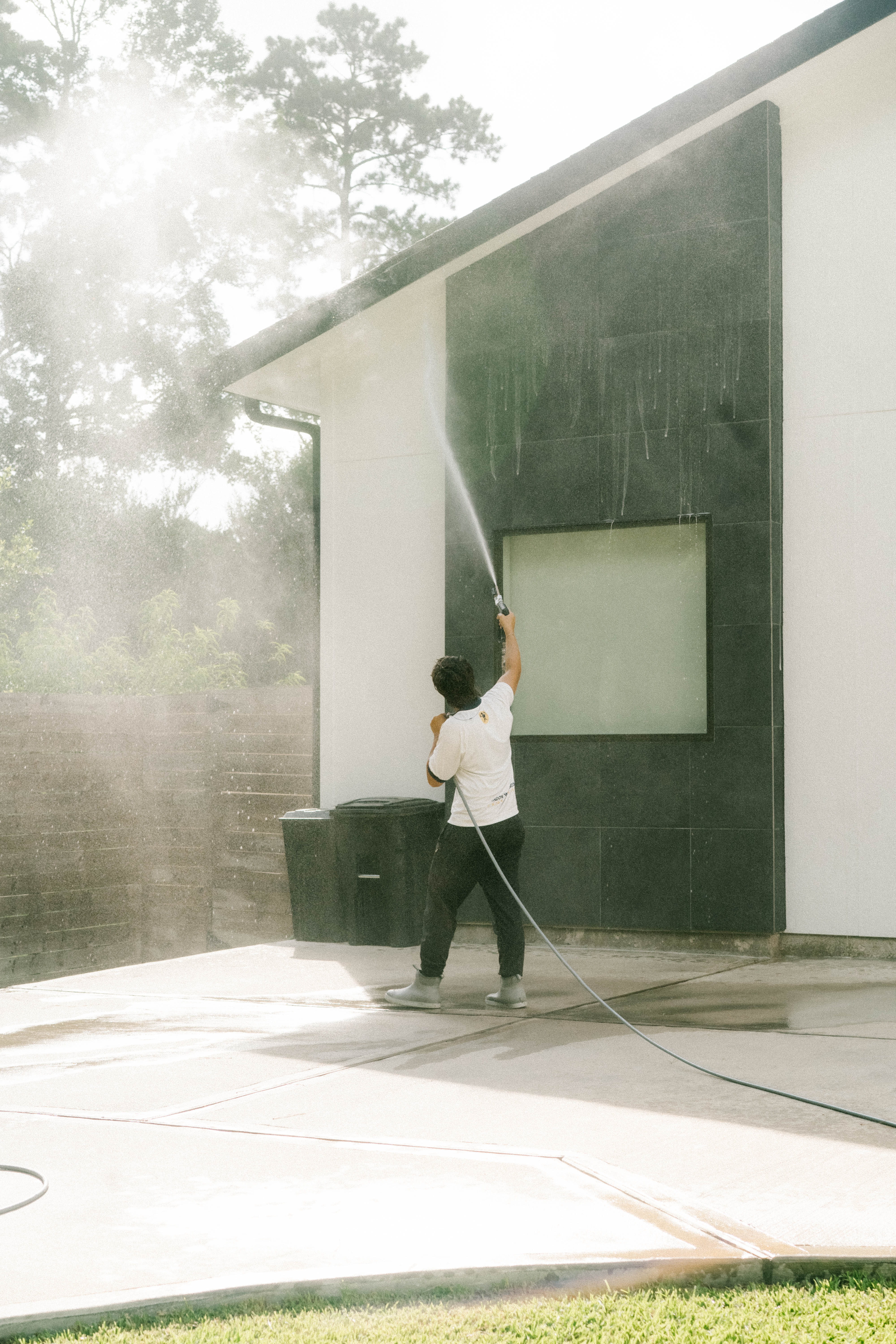Pressure washing dark stone siding on a modern Houston home