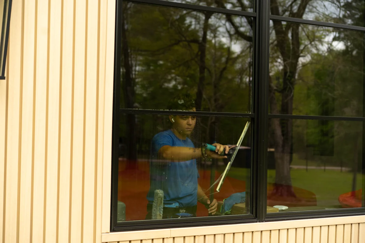 Window Warriors technician cleaning interior glass with a squeegee