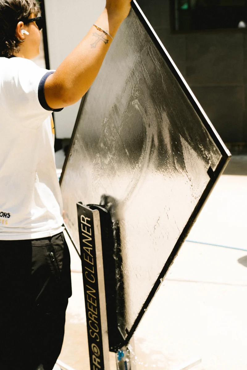 Window Warriors technician cleaning a window screen with a dedicated screen cleaning tool